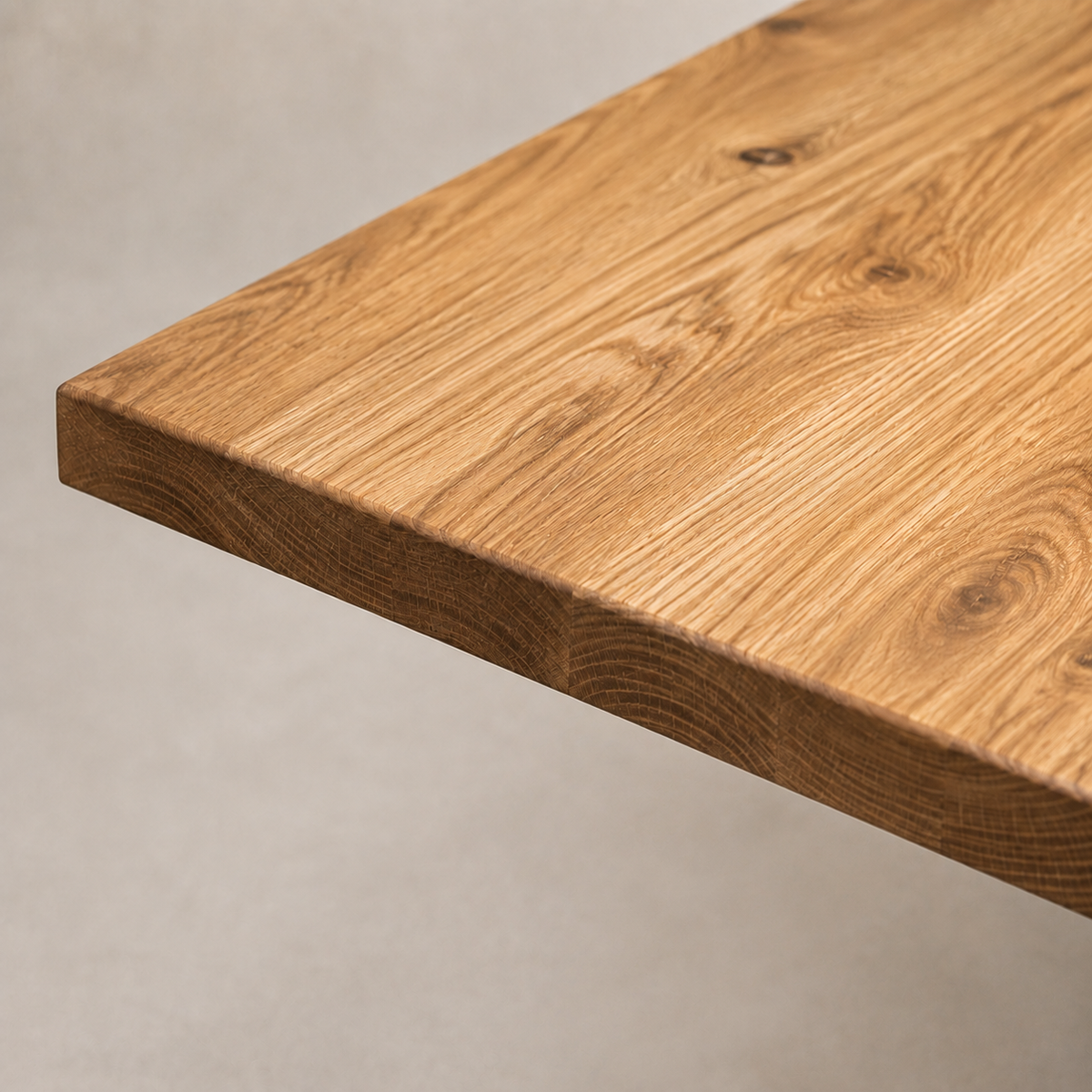 Close-up of a natural oak wood tabletop corner showing the grain and finish against a neutral light gray background.