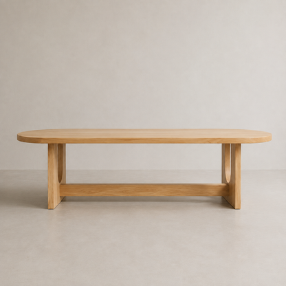 A minimalist light elm wood dining table with a rounded rectangular top, integrated legs, and a lower support rail, set against a neutral beige studio background.