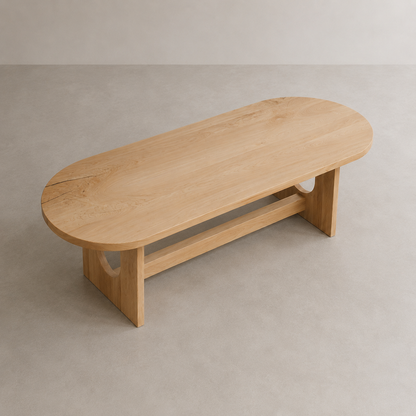 A minimalist oval wooden dining table with a natural elm finish, featuring a lower support rail and cutout legs, set against a neutral concrete floor and wall.