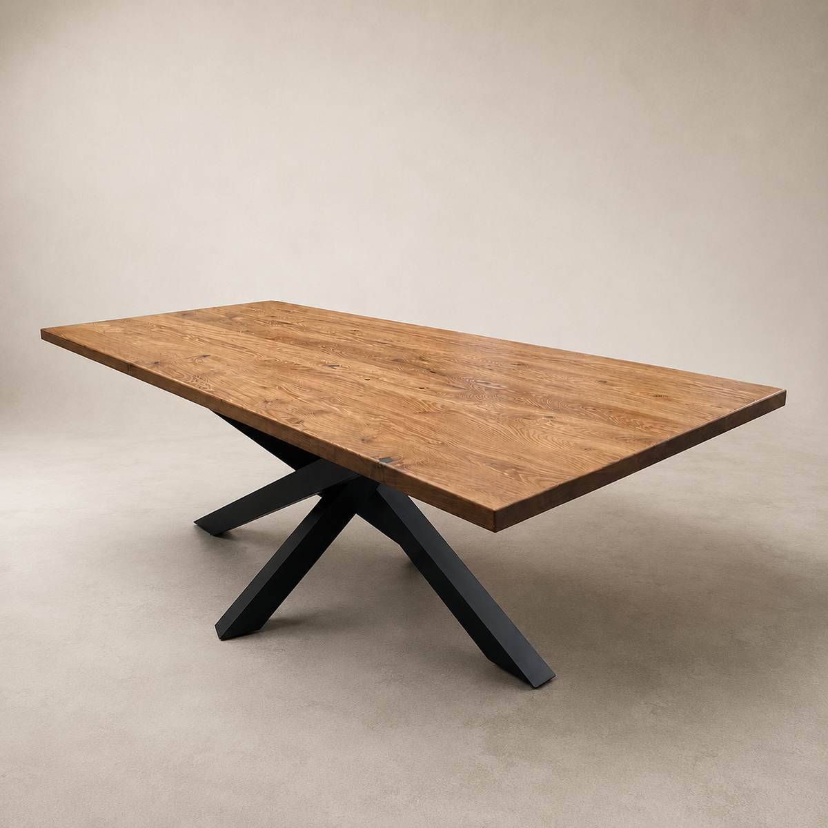 A rectangular wooden dining table with a warm medium-brown wood grain top and a black metal X-shaped pedestal base, photographed in a minimalist studio setting with a beige background.
