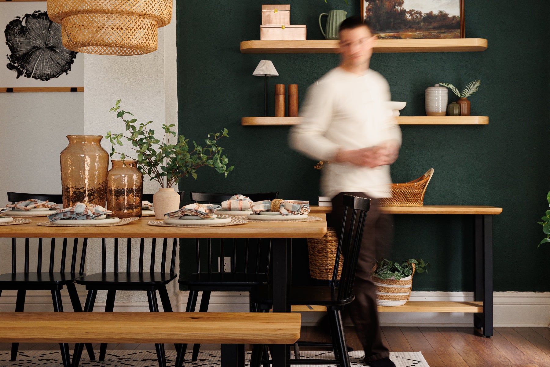 Dining room with wooden table, chairs, and shelves against a dark green wall.