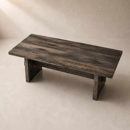 A rustic rectangular wooden coffee table with a dark weathered finish and block-style legs, photographed in a minimalist studio setting with a warm beige background.