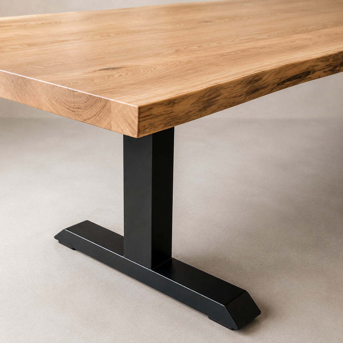 A close-up of a modern table featuring a thick, live-edge natural elm wood top with visible grain, supported by a matte black T-style metal pedestal base on a neutral concrete floor.