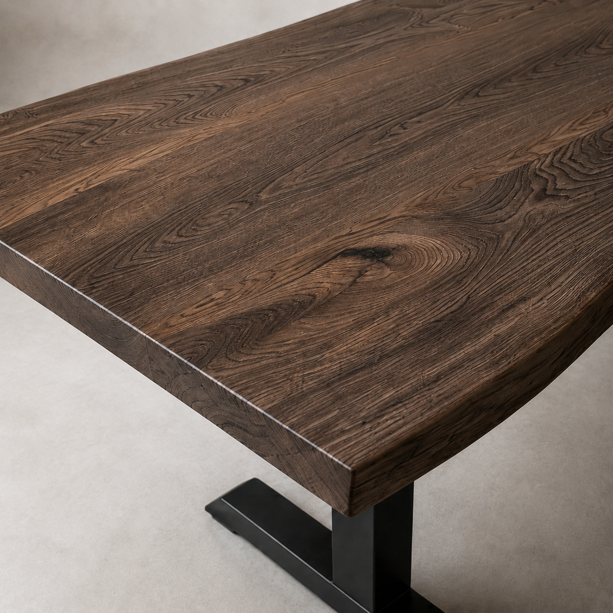 A close-up of a dark brown live-edge wooden table with a black metal pedestal base, shown on a neutral light gray floor.
