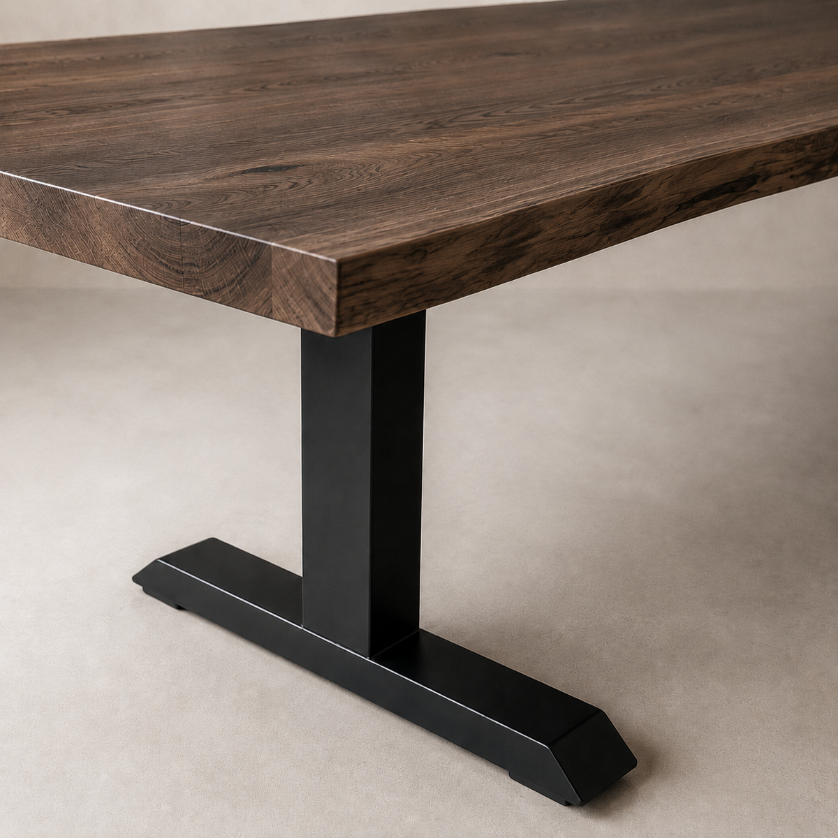 A close-up of a modern dining table featuring a thick, dark brown wood grain top and a matte black T-style metal pedestal base, set against a neutral beige background.