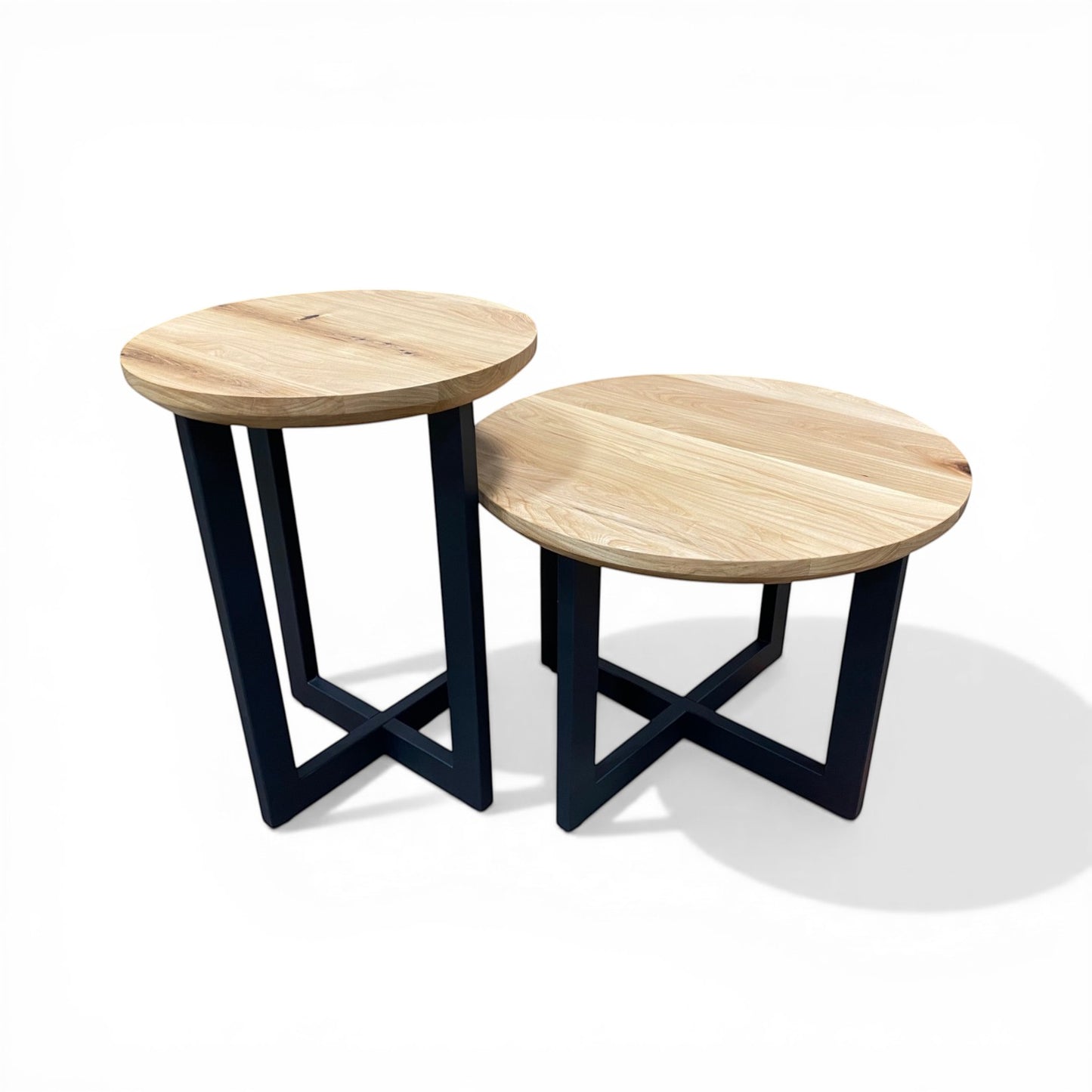 Urban Lumber set of two round nesting accent tables with natural wood tops and black metal bases.