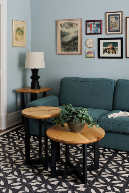 Urban Lumber nesting accent tables with natural wood tops and black metal bases. One table holds a potted plant.