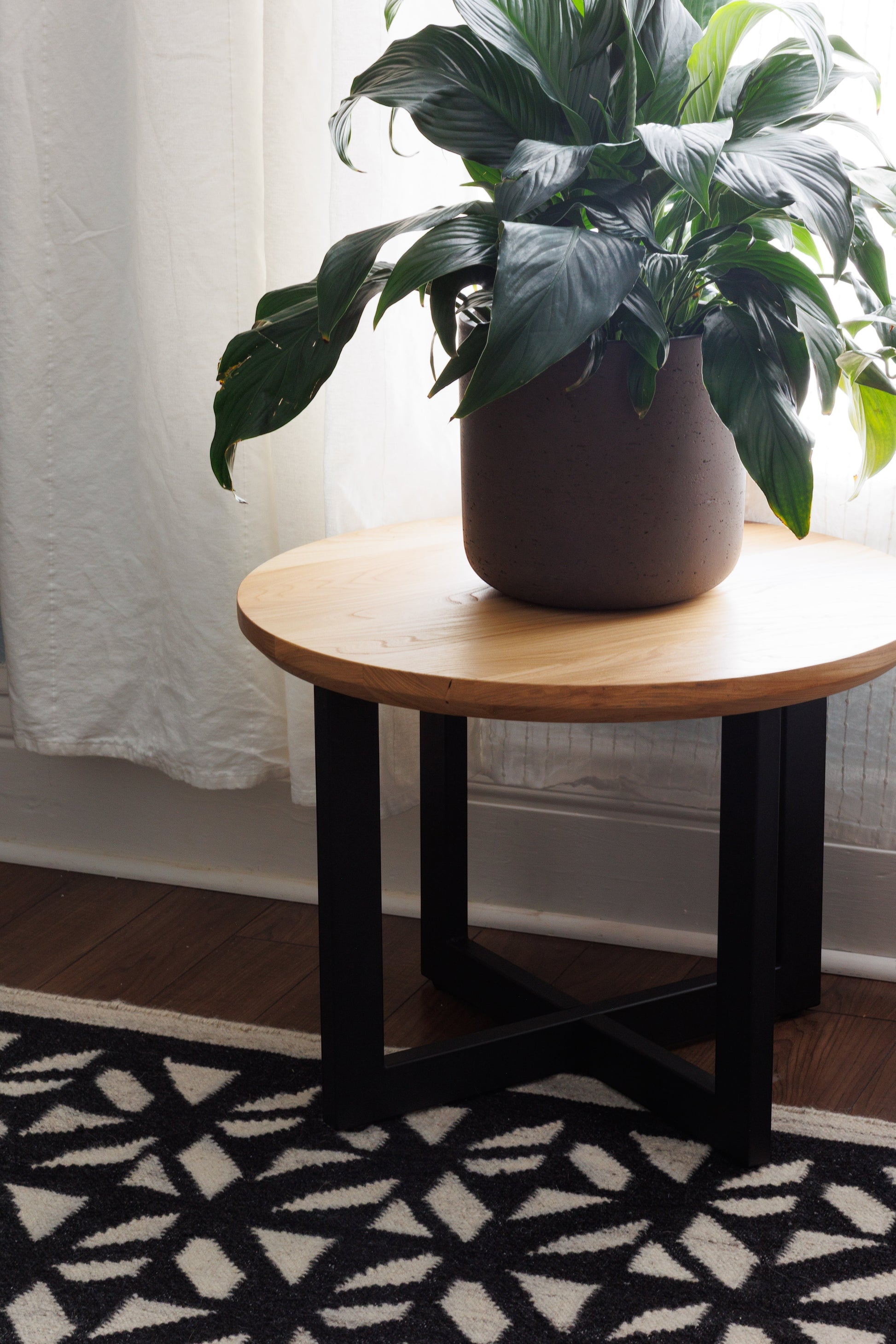 Urban Lumber classic round coffee table made from salvaged elm wood with black metal base. Features natural wood grain.